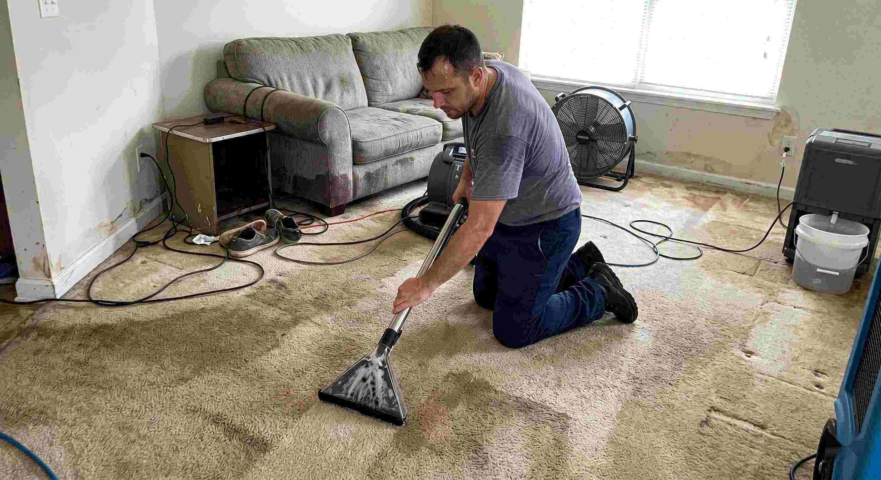 Technician performing carpet water extraction in a residential home using professional equipment after water damage in Baltimore